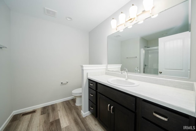 bathroom featuring vanity, toilet, a shower with shower door, and hardwood / wood-style floors