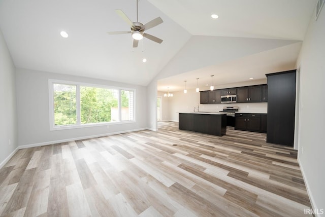 unfurnished living room with light hardwood / wood-style flooring, high vaulted ceiling, and ceiling fan with notable chandelier