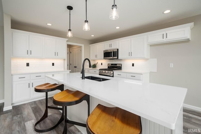 kitchen featuring white cabinets, stainless steel appliances, a center island with sink, and dark hardwood / wood-style floors