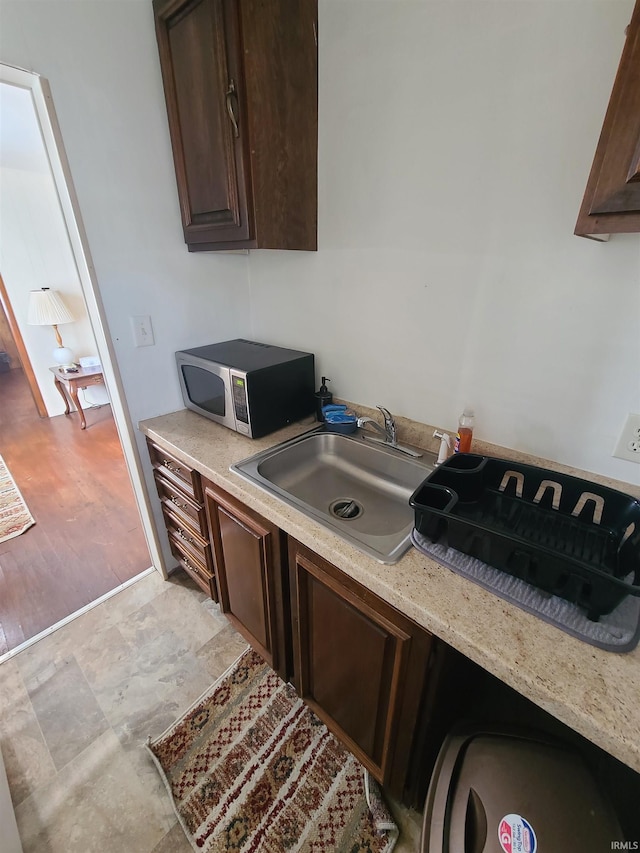 kitchen featuring sink, light stone countertops, and dark brown cabinetry