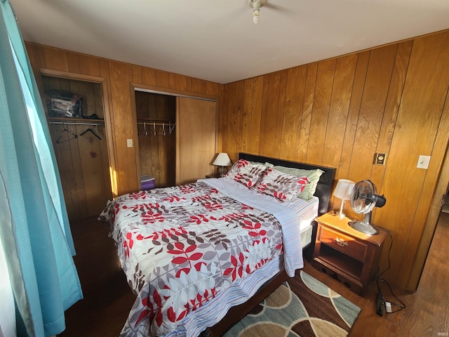 bedroom with dark hardwood / wood-style flooring, a closet, and wood walls