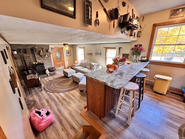 kitchen featuring a baseboard radiator, a wood stove, a textured ceiling, ceiling fan, and hardwood / wood-style flooring