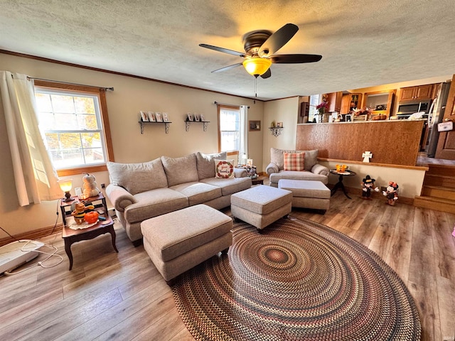 living room with light hardwood / wood-style flooring, a textured ceiling, and ceiling fan