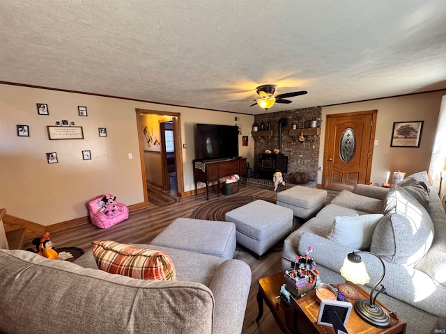 living room with a wood stove, a textured ceiling, hardwood / wood-style flooring, and ceiling fan