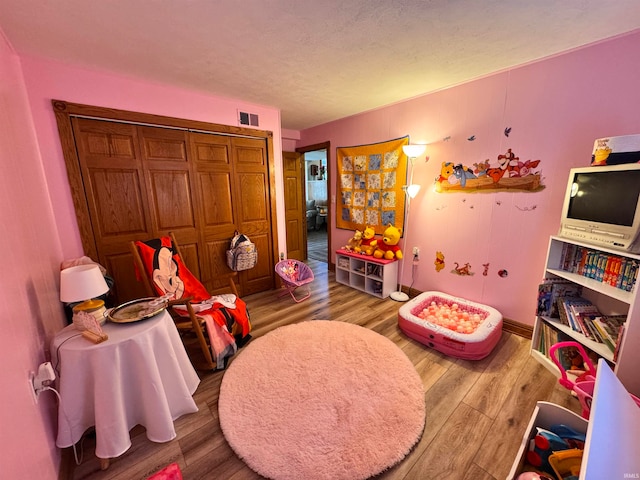 playroom featuring a textured ceiling and hardwood / wood-style flooring