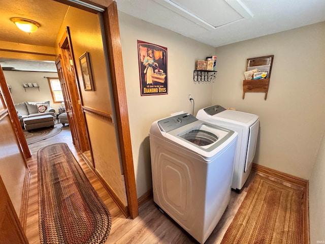 washroom with light hardwood / wood-style floors and washer and dryer