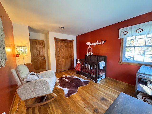 bedroom featuring a closet, wood-type flooring, and a nursery area