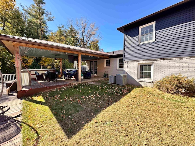 view of yard with a deck, central AC unit, and ceiling fan