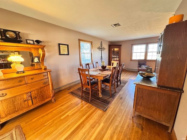 dining space with light hardwood / wood-style floors and a baseboard heating unit