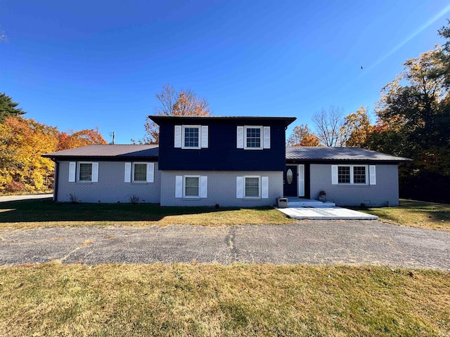 split level home with a patio area, a front lawn, and central AC unit