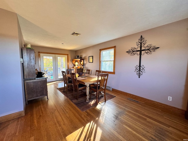 dining space with a textured ceiling, wood-type flooring, and a healthy amount of sunlight