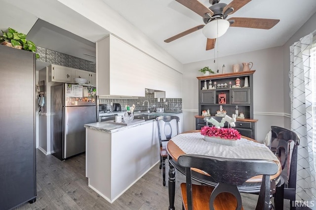 dining area featuring ceiling fan, sink, and dark hardwood / wood-style flooring