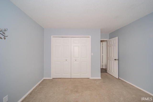 unfurnished bedroom featuring a closet, a textured ceiling, and light colored carpet