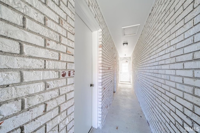 hallway featuring brick wall and concrete flooring