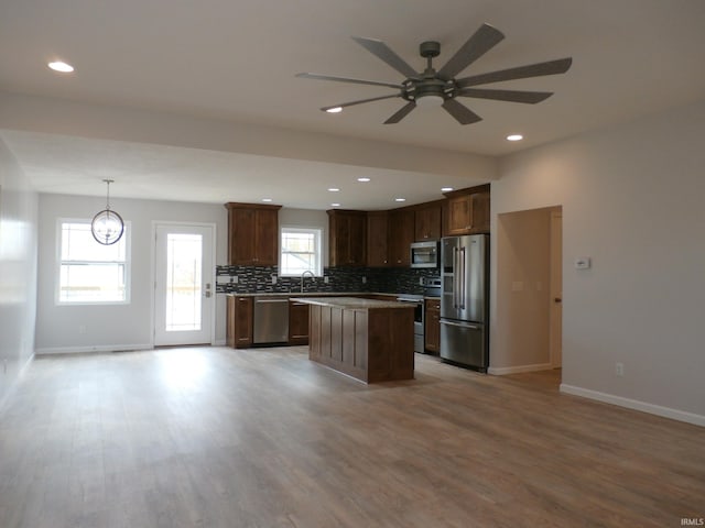 kitchen featuring a healthy amount of sunlight, appliances with stainless steel finishes, a center island, and light wood-type flooring