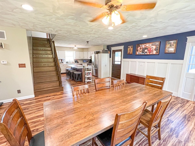 dining area with light wood-type flooring, a textured ceiling, and ceiling fan