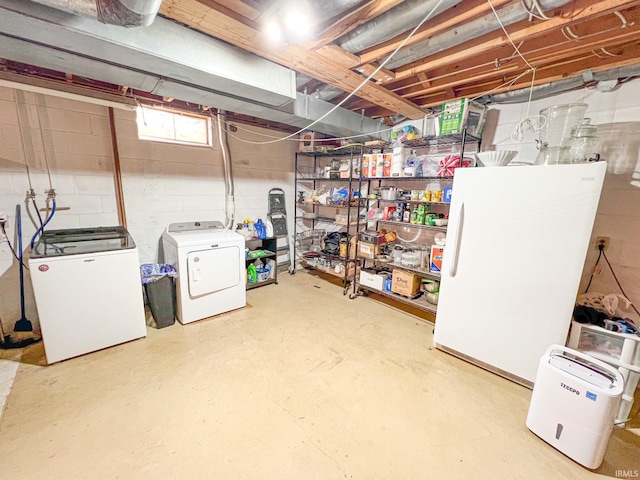 basement featuring washing machine and clothes dryer and white fridge