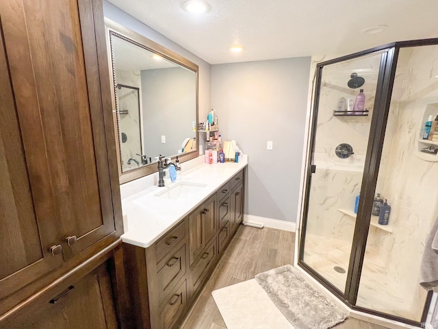 bathroom with wood-type flooring, vanity, a textured ceiling, and a shower with shower door