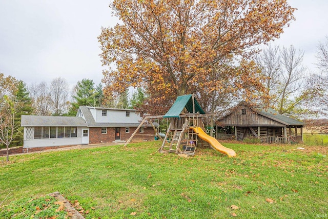 back of house with a playground, a lawn, and a sunroom