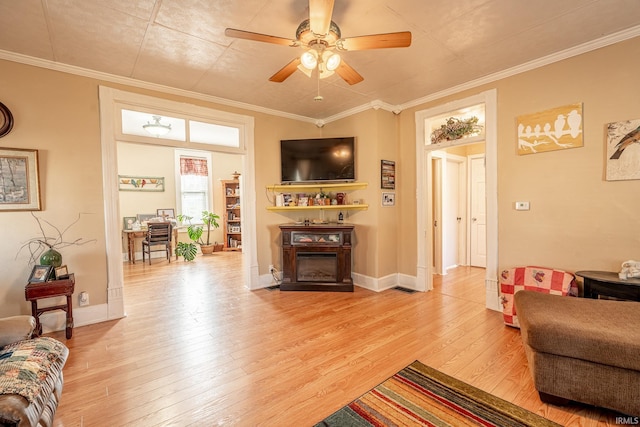 living room with ornamental molding, light hardwood / wood-style flooring, and ceiling fan