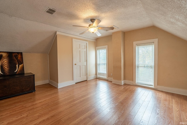 bonus room featuring ceiling fan, lofted ceiling, a textured ceiling, and light hardwood / wood-style flooring