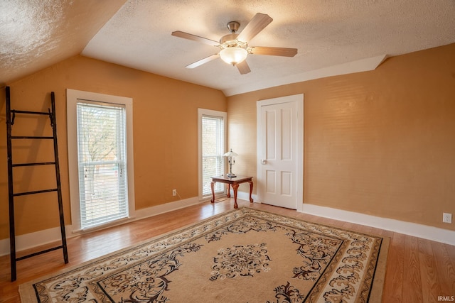 spare room featuring a textured ceiling, a wealth of natural light, and hardwood / wood-style floors