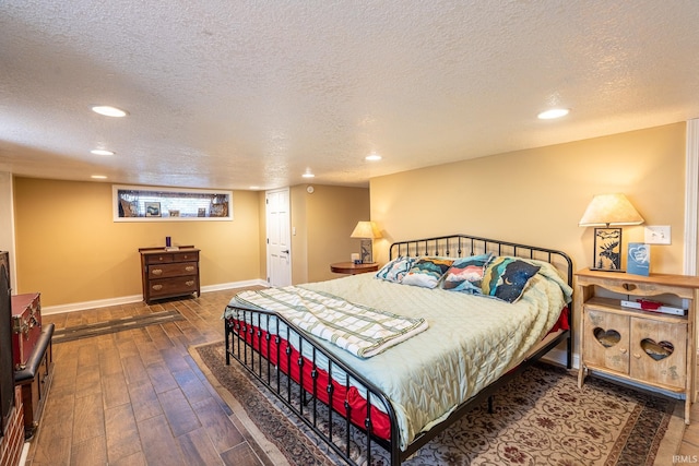 bedroom with a textured ceiling and dark hardwood / wood-style flooring