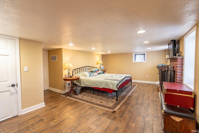 bedroom with a textured ceiling, a fireplace, and dark hardwood / wood-style floors