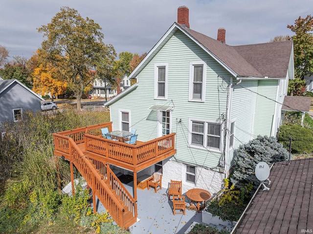 rear view of property featuring a wooden deck and a patio