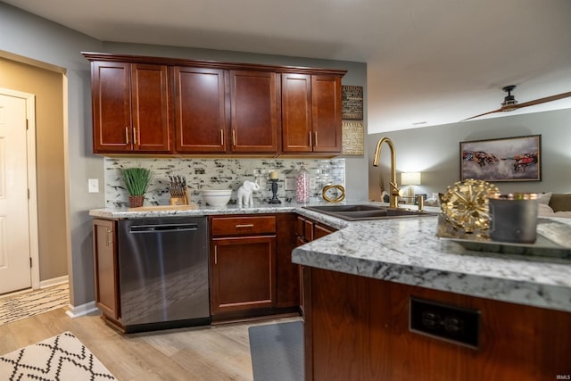 kitchen featuring sink, light stone countertops, light wood-type flooring, stainless steel dishwasher, and tasteful backsplash