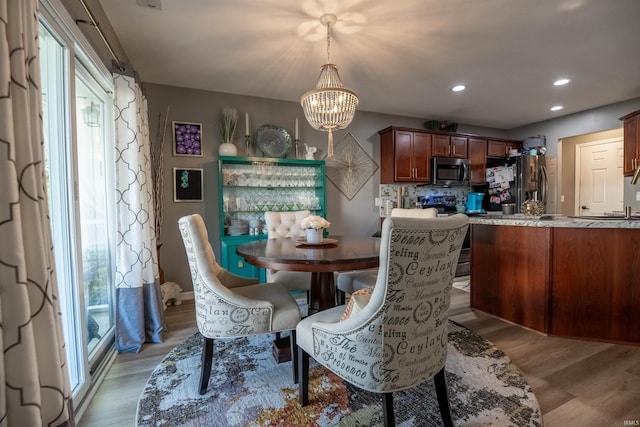 dining area with an inviting chandelier and light hardwood / wood-style flooring