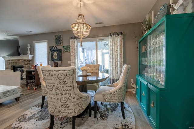 dining room featuring light hardwood / wood-style floors, a notable chandelier, and a fireplace