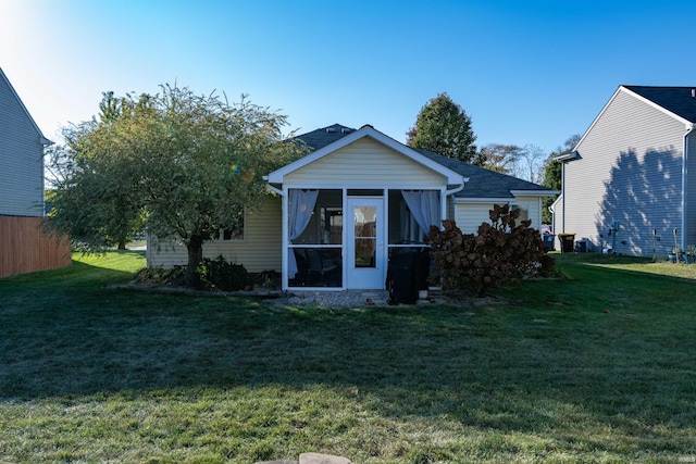 rear view of property featuring a yard and a sunroom