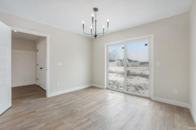 unfurnished dining area with an inviting chandelier and light hardwood / wood-style floors