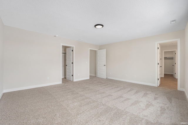 unfurnished room with a textured ceiling and light colored carpet