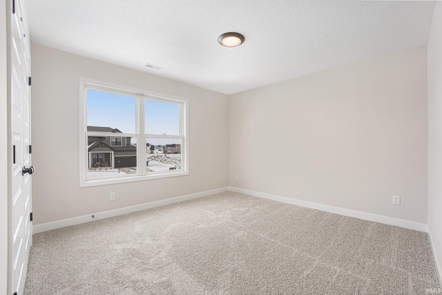 unfurnished room with carpet flooring and a textured ceiling