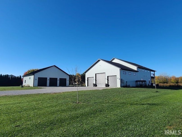 view of side of property with an outdoor structure, a garage, and a lawn