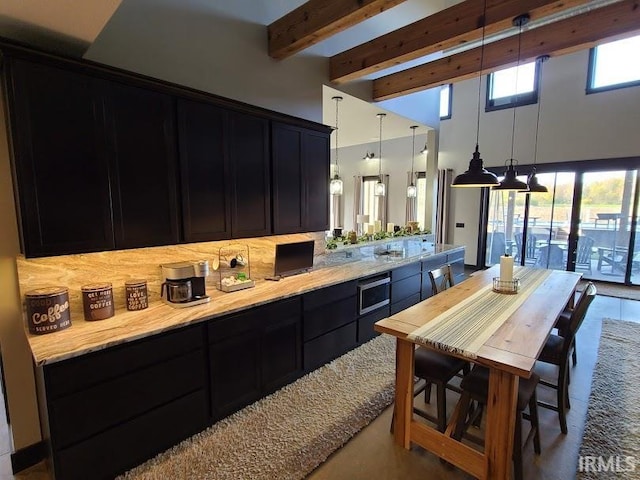 kitchen with beamed ceiling, decorative backsplash, pendant lighting, and plenty of natural light