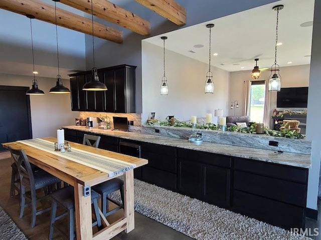 kitchen with light stone counters, beamed ceiling, and pendant lighting