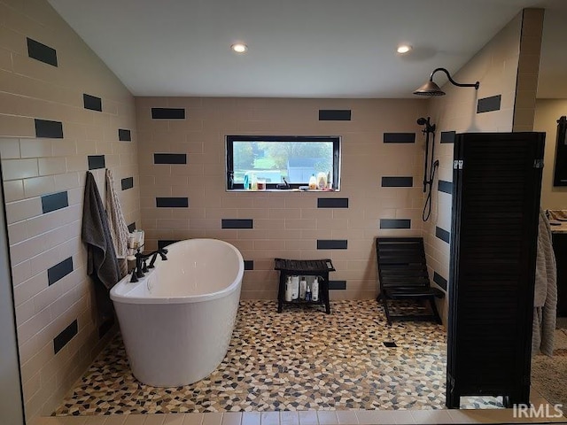 bathroom with tile walls, separate shower and tub, lofted ceiling, and tile patterned flooring