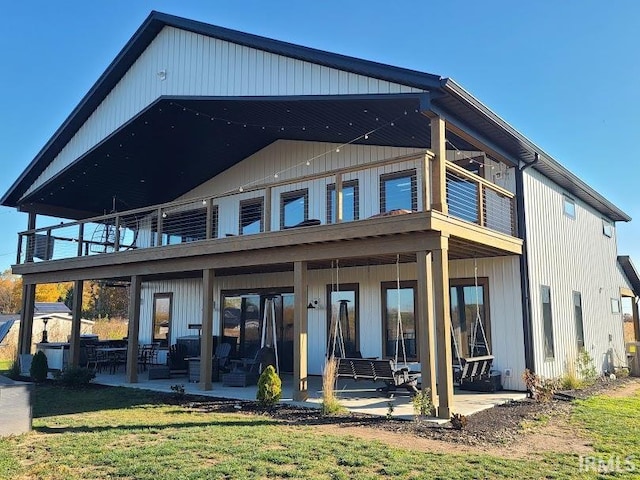 back of house featuring a patio, a lawn, and a balcony