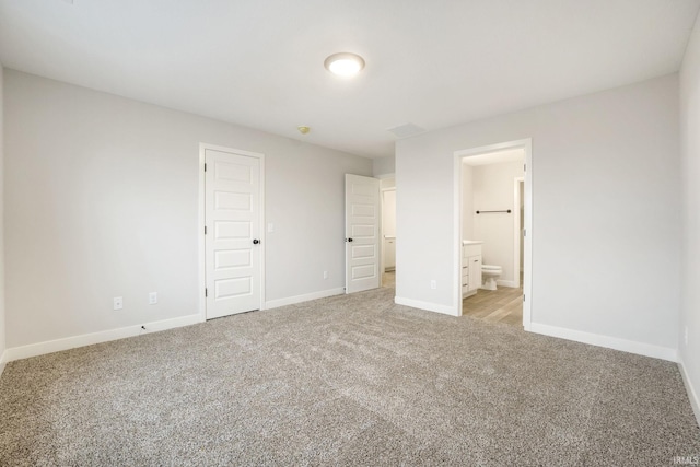 unfurnished bedroom featuring light carpet and ensuite bathroom