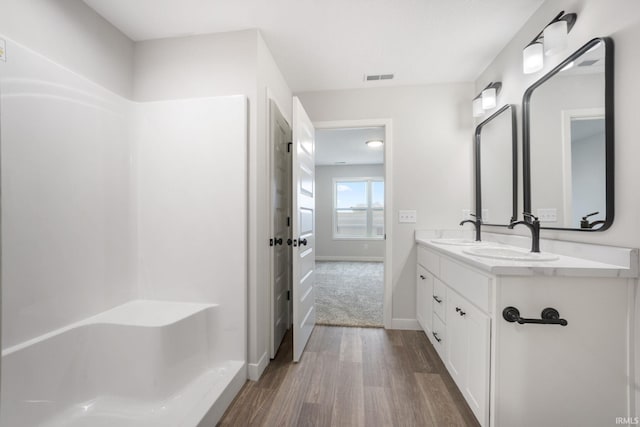 bathroom featuring hardwood / wood-style flooring, a shower, and vanity