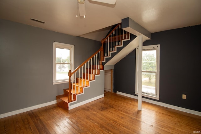 stairs with hardwood / wood-style flooring and ceiling fan