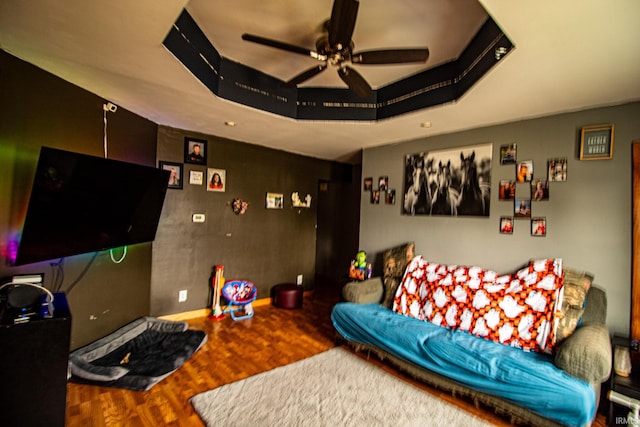 living room with ceiling fan and a raised ceiling