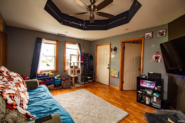 living room featuring ceiling fan, hardwood / wood-style flooring, and a raised ceiling