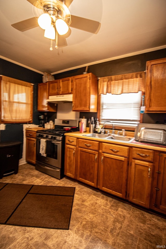 kitchen with ornamental molding, sink, gas stove, and ceiling fan