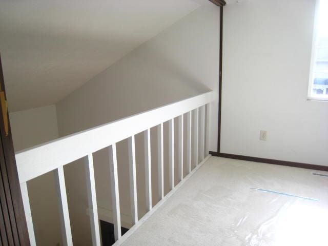 hall featuring vaulted ceiling and light carpet