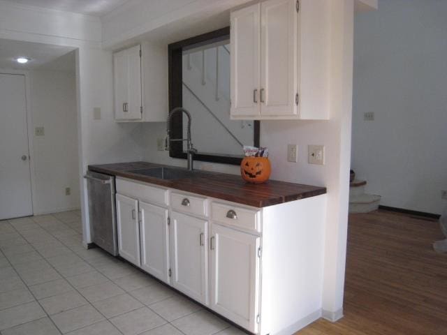 kitchen with sink, dishwasher, white cabinetry, and light wood-type flooring