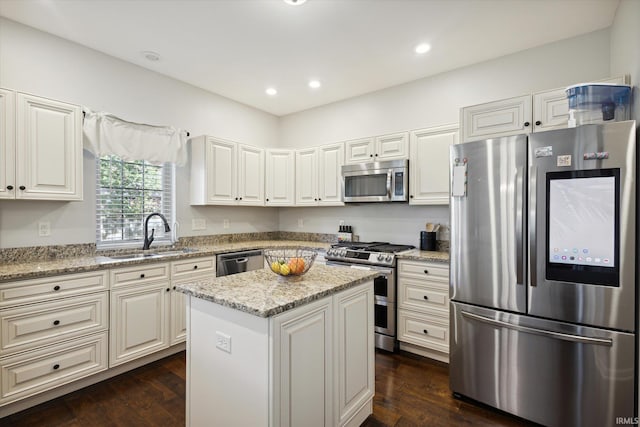 kitchen with a kitchen island, sink, appliances with stainless steel finishes, light stone counters, and dark hardwood / wood-style flooring